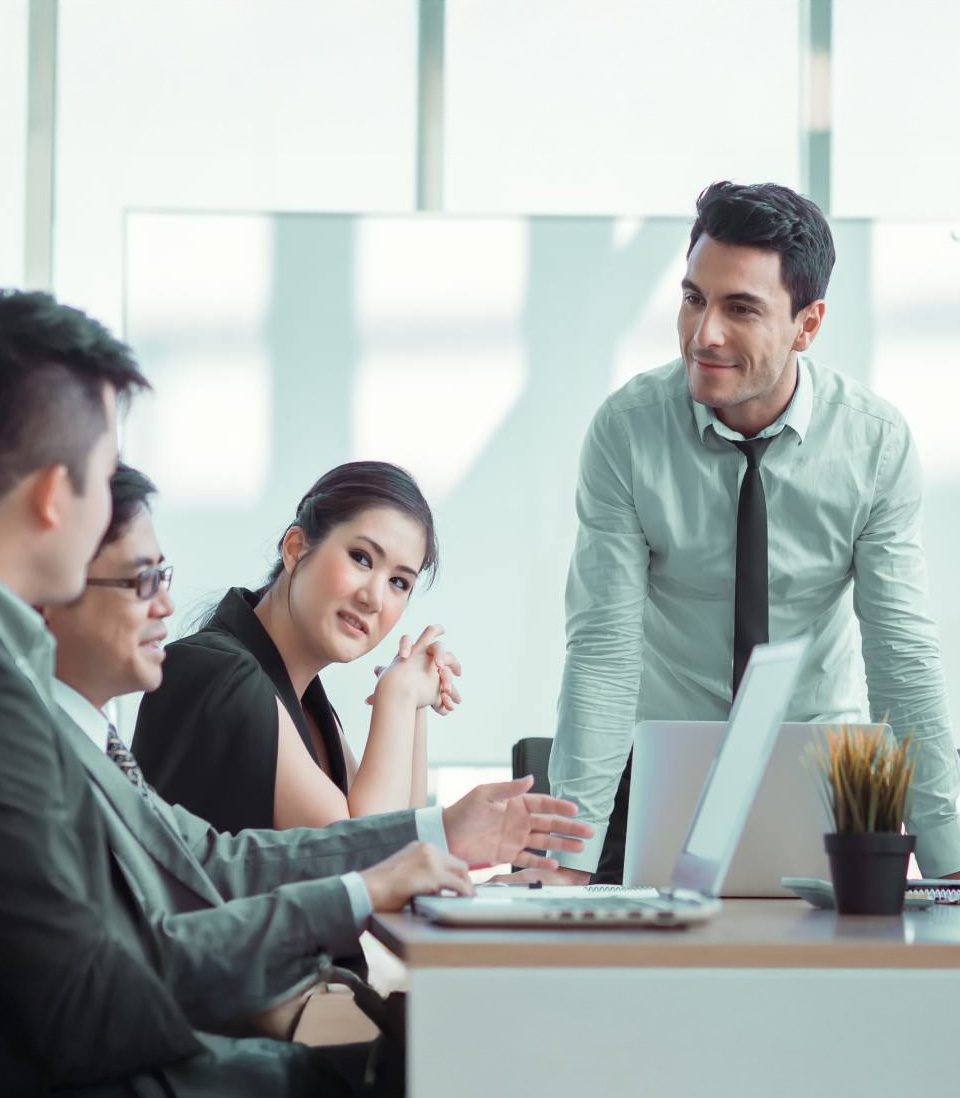 A professional business meeting with a group of colleagues discussing around a table.