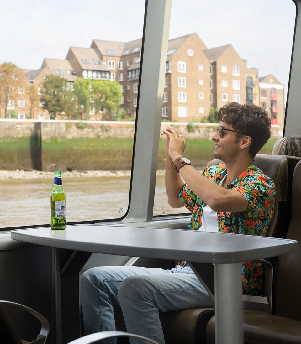 Man in tropical shirt taking photos on a river ferry.