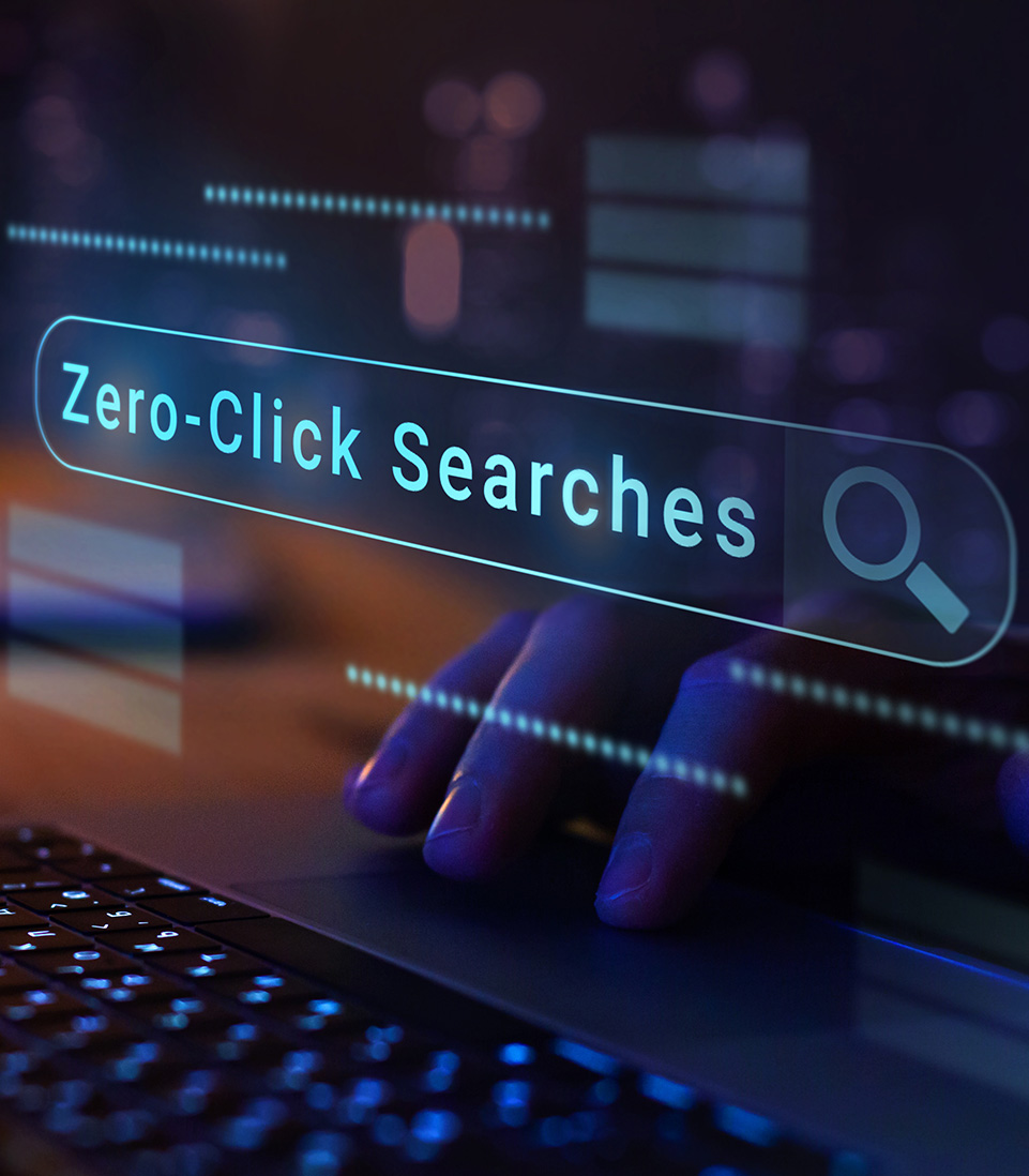 A close-up of a hand typing on a laptop keyboard with a glowing digital search bar overlay reading “Zero-Click Searches.”