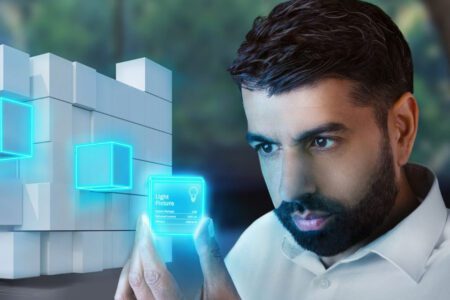 A man in a white shirt examines a futuristic holographic interface displaying data, with glowing blue digital elements integrated into a modern architectural background.