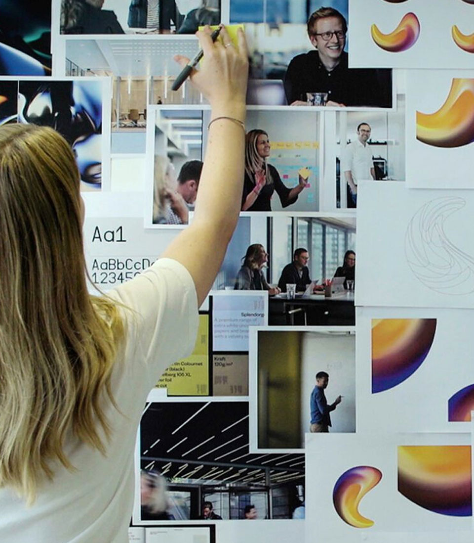 A creative professional arranges branding materials and concept visuals on a mood board, refining a design strategy.