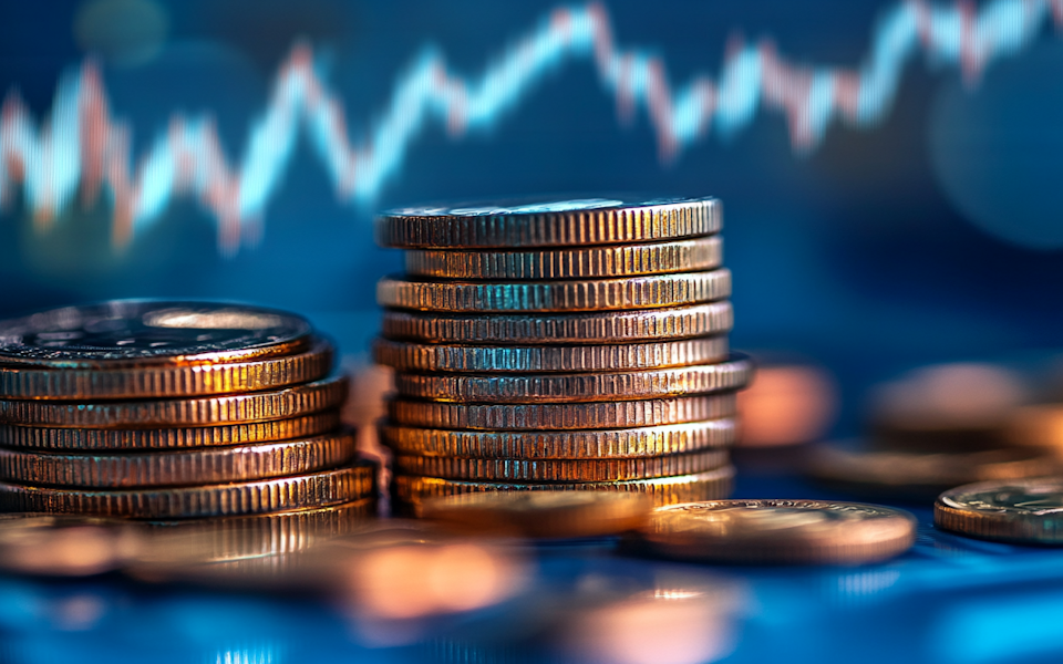 Pile of coins against a graph-effect background depicting growth.