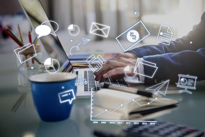 Person typing on a laptop with digital icons of charts, files, and communication symbols overlaid, representing data, strategy, and business technology.