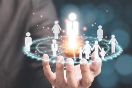 A businessperson holding a digital hologram of people icons, symbolising audience understanding and customer connection in marketing.