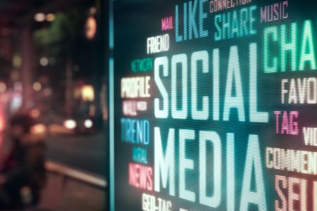 Neon social media words displayed on a city street at night